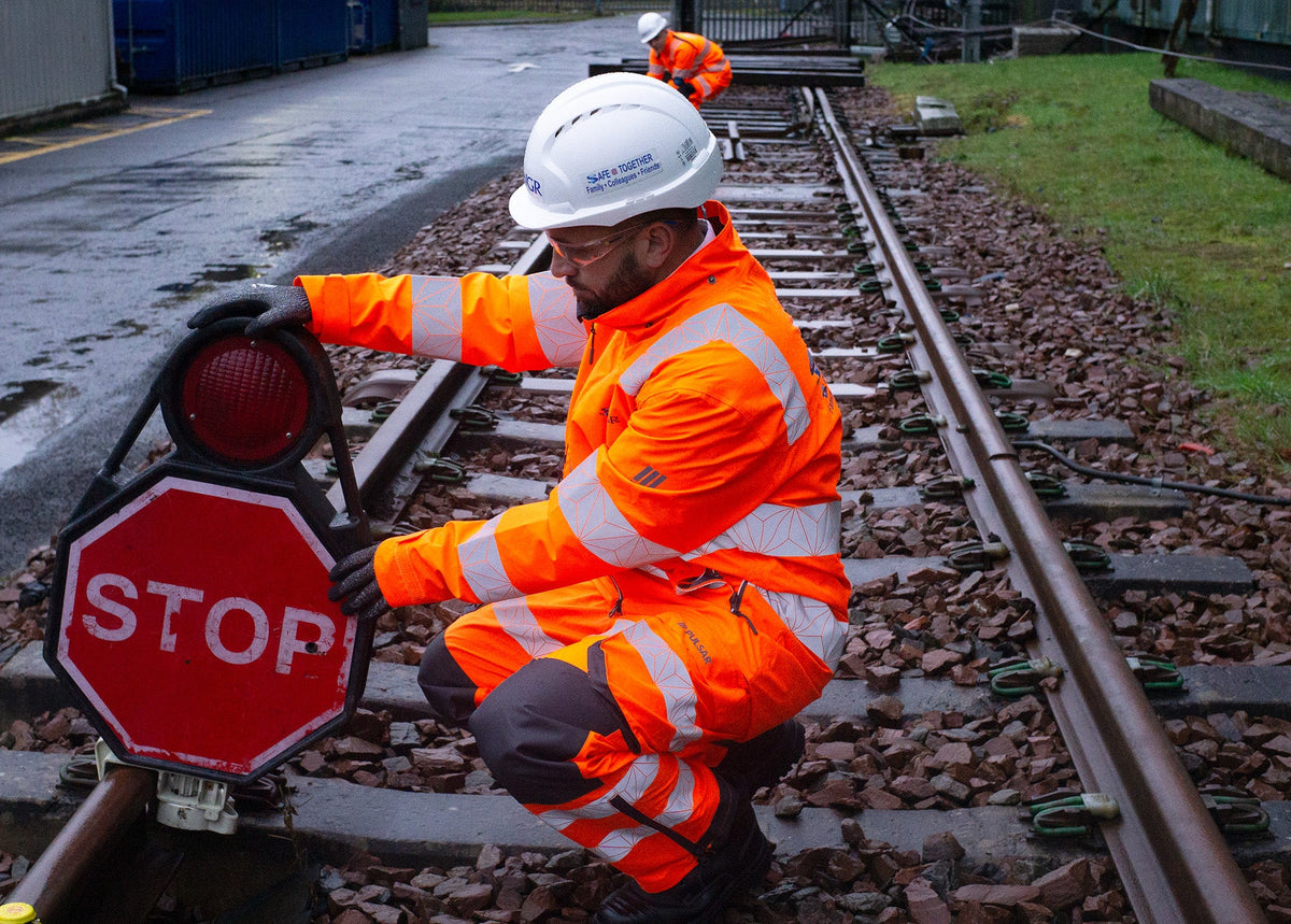 Rail worker in PULSAR orange hi-vis jacket and trousers beside the track