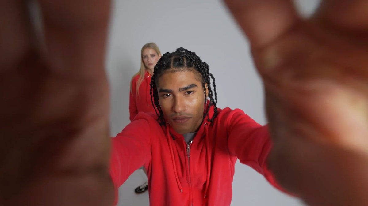 Two people in red Anthem tops, one framing the camera with his hands