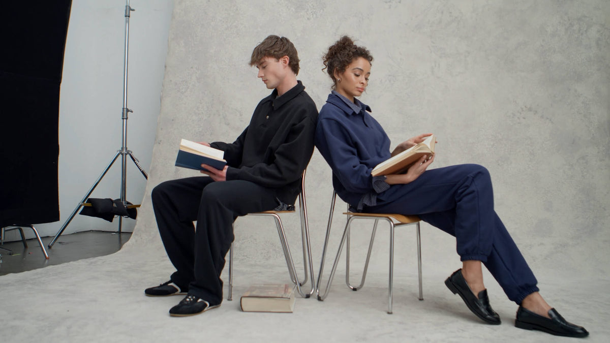 Two people seated back to back in Bella+Canvas clothing
